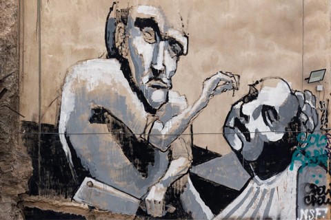 Figure with cleaver rips out man's tooth, graffiti in Exarchia, neighbourhood of students and