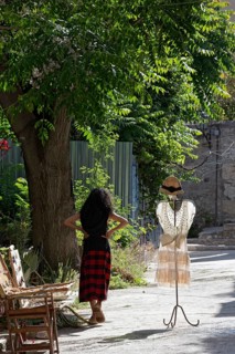 Clothes rack with summer dress in the morning light, placed in front of a fashion boutique, woman