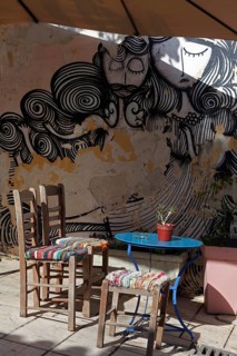 Chairs and table in front of a wall with graffiti, taverna in the old town district of Plaka,