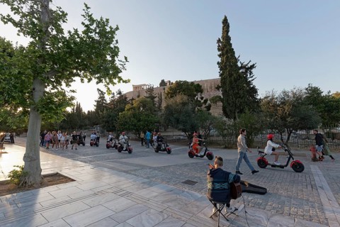 Row of tourists riding on e-chopper on Dionysiou Areopagitou, pedestrian street with view of the