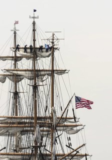 New London, Connecticut, USA, July 2012: Crew members high up in the rigging furl the sails on the