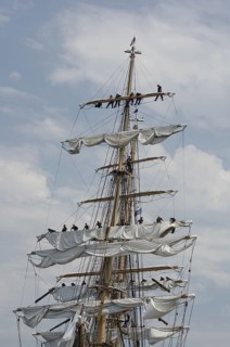 New London, Connecticut, USA, July 2012: Crew members high up in the rigging furl the sails on the