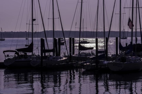 Sailboats in silhouette moored at a dock with a purple sunrise. Niantic, East Lyme, Connecticut,