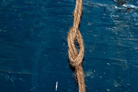 Nautical rope knot on blue wooden background