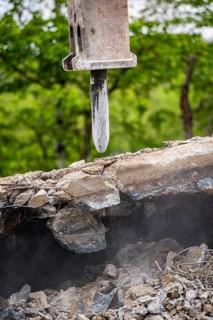 Close-up of the excavator as it breaks up concrete on a construction site. Debris and dust are