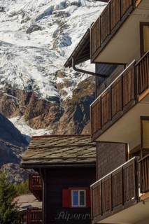Wooden balconies in a mountain village, with snow-capped mountains in the background, Saas Fee,