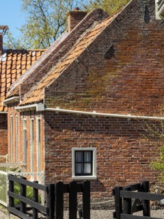 A rustic brick building with a wooden fence and bricks, in a rural setting, enkhuizen, the