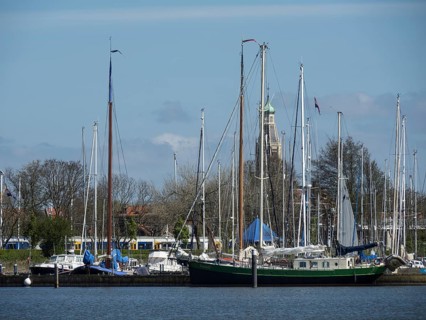 View of a harbour with sailing boats and a historic bell tower in the background, calm water,