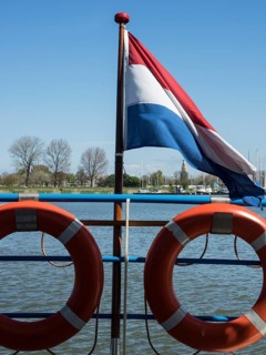 Dutch flag and lifebuoys on a jetty under a clear sky, enkhuizen, the netherlands