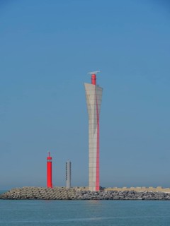 Three lighthouses in red and white on the coast, in front of a blue sky and calm sea, oostende,