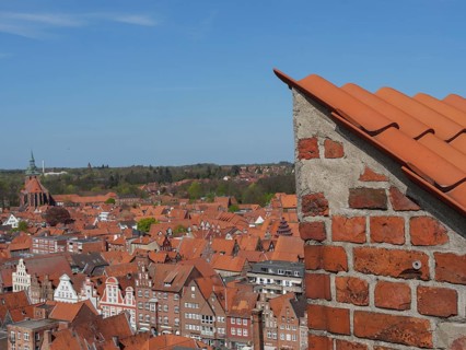 View over the red roofs of a city, calm and clear view with church tower in the background, view