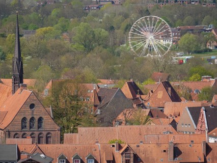 Cityscape with church tower, red roofs, green foliage and a holiday bike in the background under a