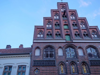 A historic brick building with an elaborately decorated faÃ§ade and many windows against a blue