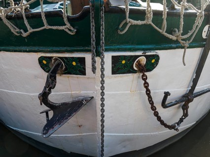 Close-up of a boat bow with anchor, chains and rope. Maritime decoration in green and white, Leer,
