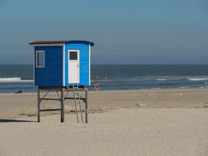 Blue lifeguard tower on sandy beach with calm sea and people in the background, langeoog, germany