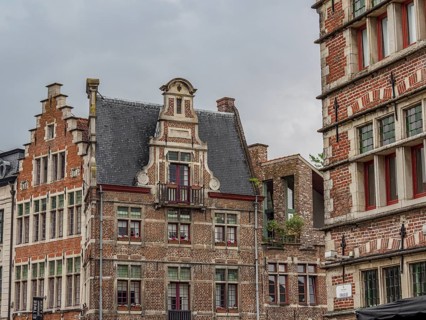 Multi-storey historic buildings with detailed facades and gables, under a cloudy sky, Ghent,