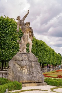 An imposing stone statue in front of an avenue of trees in a historic park, Salzburg, Austria,