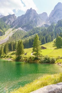 A tranquil lake in an idyllic mountain landscape, surrounded by meadows and forests under a clear
