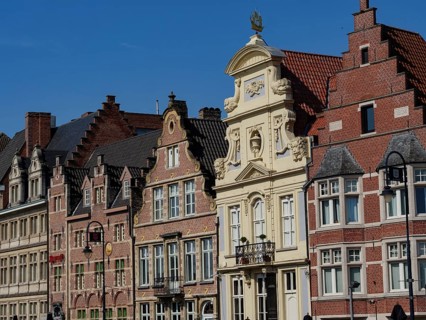 Row of old brick buildings with distinctive gables and window frames on a sunny day, gent, belgium