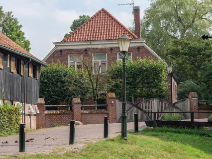 A cosy brick house with an old street lamp and a small bridge in a green garden, haaksbergen, .