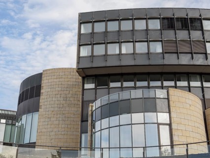 Modern building with glass facades and round design under a slightly cloudy sky, Düsseldorf, North