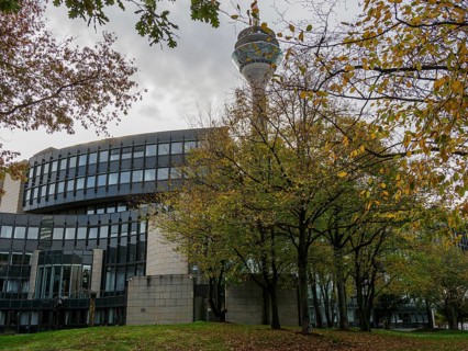 Modern architecture of a building and the television tower, surrounded by autumnal trees and a