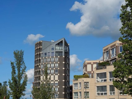 Tall, modern residential tower and neighbouring buildings in the middle of an urban landscape with