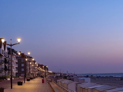 An illuminated promenade with lanterns and buildings at dusk on the beach, de haan, Belgium, Europe