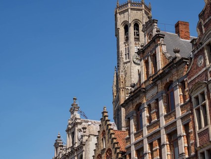 Historic buildings and tower with detailed architecture under a blue sky, Bruges, Belgium, Europe