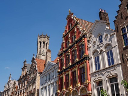 A historic street with stately brick buildings and a large tower in the background, Bruges,