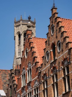 Historic brick buildings with ornate facades and a tall tower in the background, Bruges, Belgium,