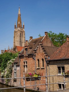 Historic buildings with brick facades and a high church tower, balcony flowers decorate the