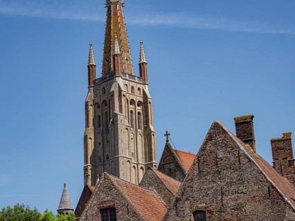Red church tower and historic buildings under a blue sky, Bruges, Belgium, Europe
