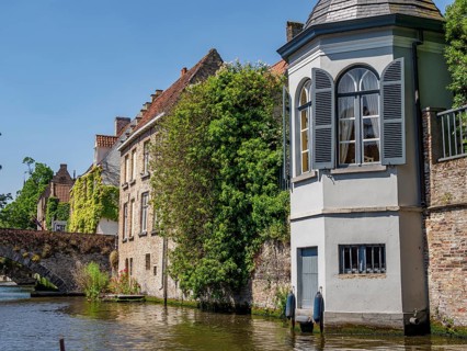 Historic houses with overgrown facades along a canal, Bruges, Belgium, Europe