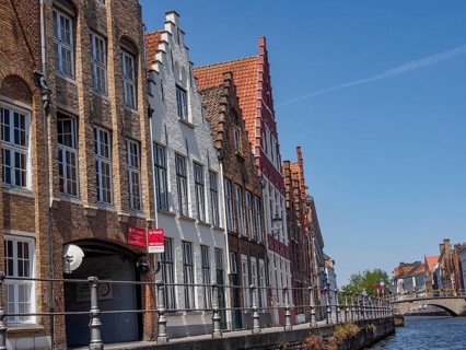 Historic buildings with red roofs and facades on the canal under a blue sky, Bruges, Belgium,