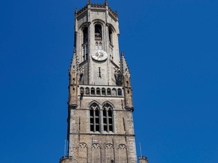 Gothic bell tower with clock in front of a slow sky, Bruges, Belgium, Europe