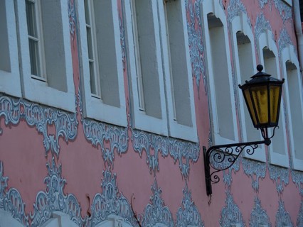 Pink baroque house facade with ornate windows and an old street lamp, trier, germany