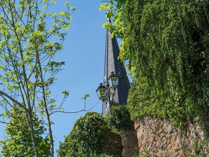Pointed gabled church tower surrounded by green trees and an old wall, Saarburg, Germany, Europe