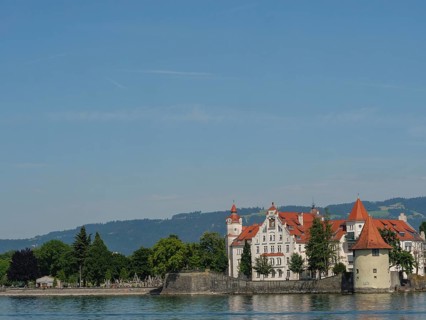 Urban scene with historic buildings and towers along the lakeshore under a clear summer sky,