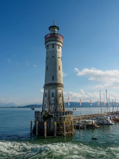 High lighthouse on the water with boats and clear sky in the background, Lindau, Bavaria, Germany,