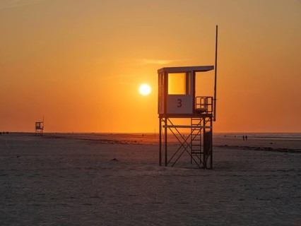 Beach at sunset with a rescue tower and calm, orange-coloured atmosphere, juist, east frisia,