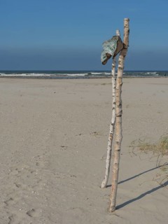 Beach with wooden poles and flag in the sand, sea in the background, blue sky, juist, east frisia,