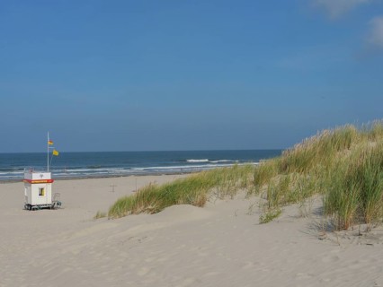 Small hut with flag on a wide sandy beach with dunes and blue sky, Juist, East Frisia, Germany,