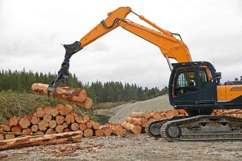 A digger driver stacks logs at a milling site in exotic forest on the West Coast, New Zealand,