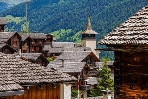 Old wooden houses with wooden shingle roofs in the historic centre of Grimentz, behind the church