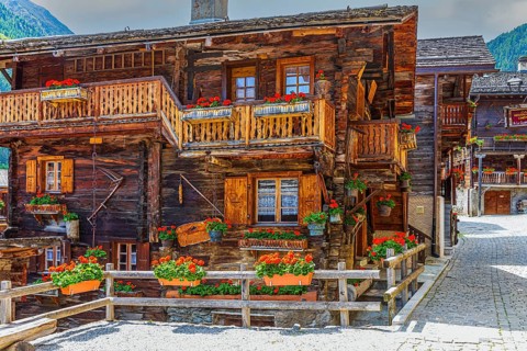 Paved footpath surrounded by old wooden houses, flower boxes on balconies and windows, historic
