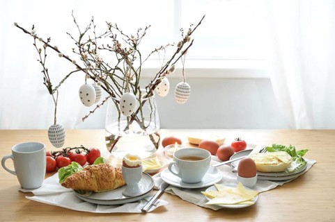Breakfast with Easter egg decoration on a wooden dining table, place setting on a spring holiday,