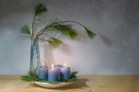 Blue candles, three lit for the third advent, and a vase with pine branches, modern decoration in