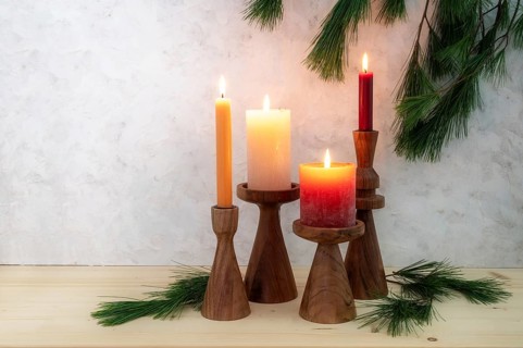 Four candles on wooden stands, all are lit for the fourth Advent, pine branch decoration, light