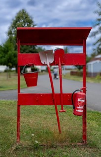 Red fire extinguishing point with fire extinguisher, shovel, spade and bucket at a campsite on Lake